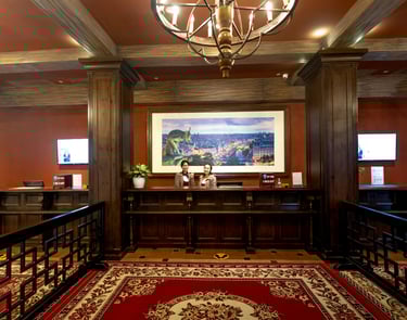 Luxury hotel lobby reception desk with friendly staff, wood paneling, and a large chandelier.