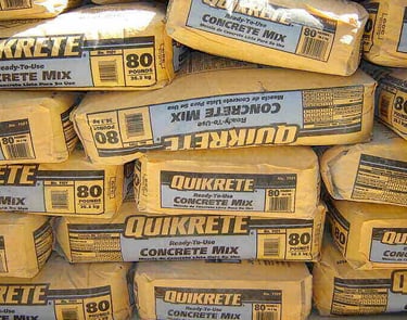 Stacked 80-pound bags of Quikrete ready-to-use concrete mix for construction projects.