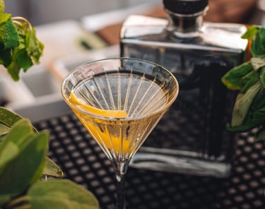 a martini glass with a tequila cocktail in it with in the back a bottle of uno tequila cristalino