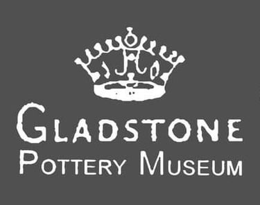 Gladstone Pottery Museum logo featuring a white crown symbol above serif text on a dark gray background.