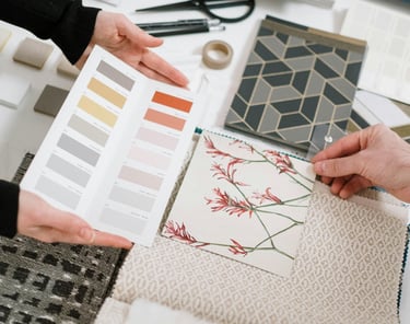 Designer de interiores apresentando amostras de decoração em uma mesa, destacando cores, texturas