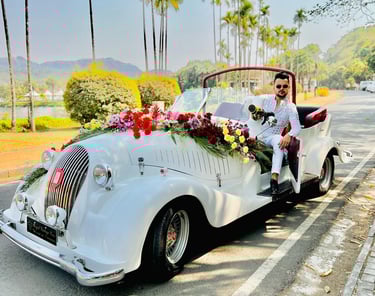 a man in a white suit and tie is sitting in a convertible car