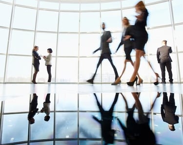 a group of business people walking through a large glass window