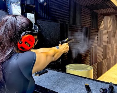 mais alhajri shooting a handgun at an indoor shooting range wearing protective gear