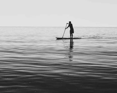 A man doing Stand Up Paddle at Two men at a group surf lesson at Santa Teresa, Costa Rica.