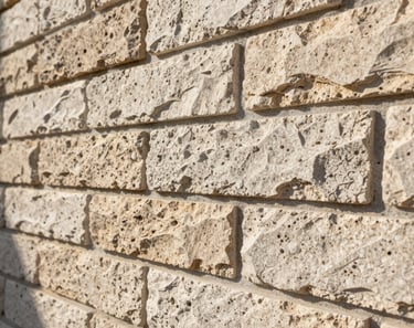 Close-up 45-degree angle shot of manufactured stone veneer wall installation in Florida afternoon sun — mortar joints tight and consistent, shadow depth showing stone relief, no people, no text