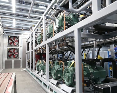Industrial refrigeration rack system with green semi-hermetic compressors and cooling fans.