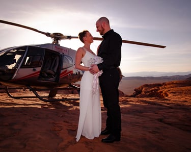 a bride and groom standing in front of a helicopter