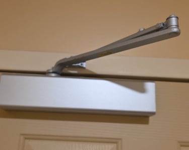 Commercial door closer installed above interior door for code compliance
