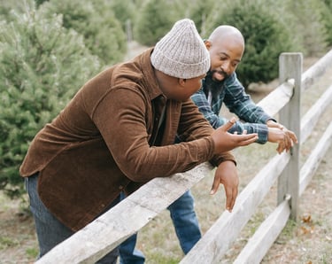 A father and son leaning with their elbows on a wooden fence having a conversation