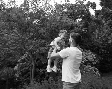 Black and white image father holding up baby boy 