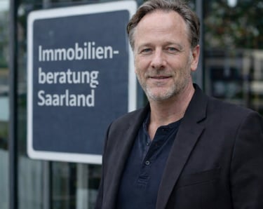 Professional real estate consultant in front of Immobilienberatung Saarland sign.