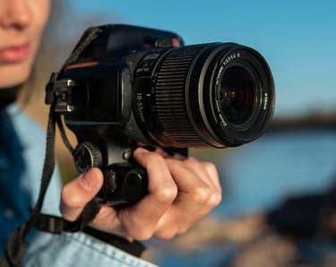 mujer sosteniendo una camara con lente