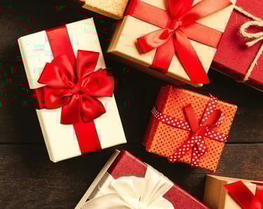 variedad de cajas de regalos con moño rojo sobre una mesa