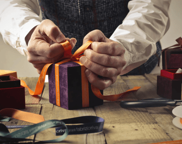 hombre acomodando un moño naranja para un regalo