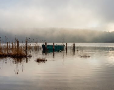 a boat on a lake with foggy sky