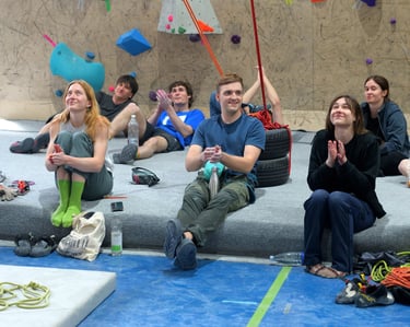 a group of people sitting on a bouldering mat