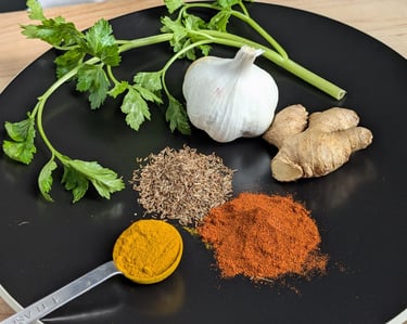 Fresh aromatics prepared for cooking, including ginger, garlic, spices and herbs