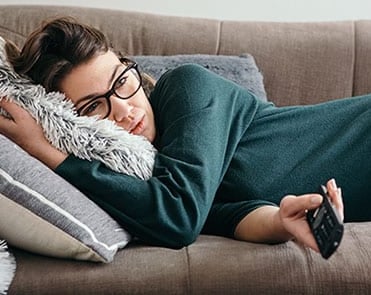 femme allongé tient une telecommande