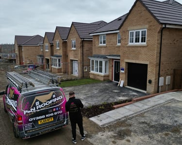Professional roofing contractor van parked in front of a new build housing development under construction.