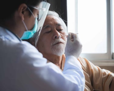 A healthcare professional in PPE performing a nasal swab test on an elderly man.