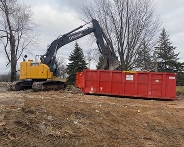 John Deere excavator putting rubble into dumpster