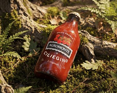 Bottiglia di Salsa Pronta di Ciliegino Agromonte con Etichetta della Terra in ambiente naturale