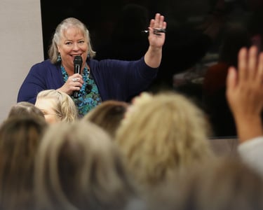 Debbie Chen speaking with a microphone to an engaged audience, Business Leadership Coach and speaker.