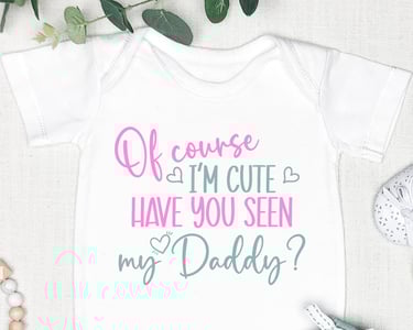 White onesie, mint baby pants, and white mj shoes, with the onesie reading "Of course I'm cute have you seen my Daddy?"