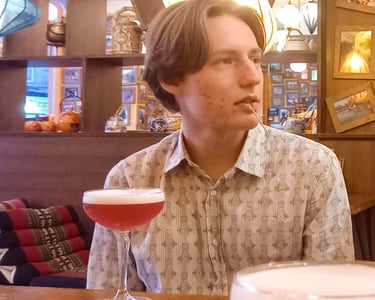Portrait shot of Byron sitting in a trendy restaurant with a drink.