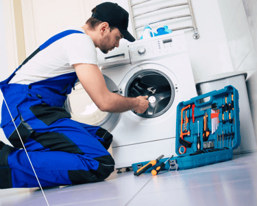 a man in overalls and overalls working on a washing machine