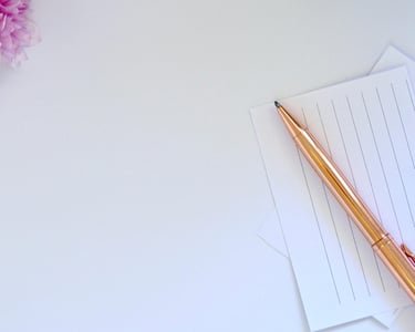Close-up of a golden pen placed on lined paper.