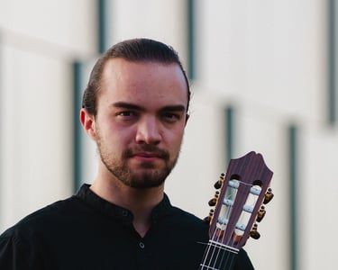 Classical guitarist Filip Babic holding guitar outside summer photo