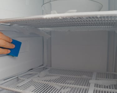 a person cleaning a refrigerator door with a sponge pad