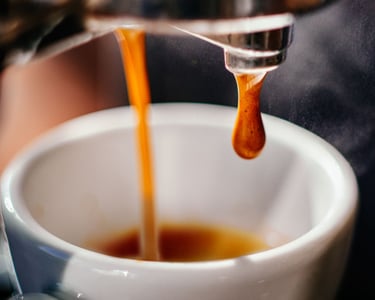 a person is pouring a cup of coffee into a cup