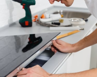 a man is fixing a stove top in a kitchen