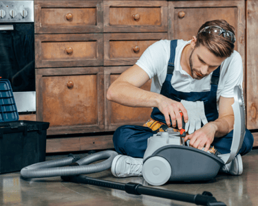 a man in overalls and overalls is cleaning a vacuum