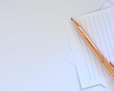 Nahaufnahme eines goldfarbenen Stifts auf liniertem Papier.