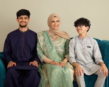 A smiling family wearing traditional South Asian Shalwar Kameez and hijab during an Eid celebration.