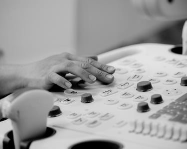 Ultrasonographer with hand on machine keyboard, operating controls.
