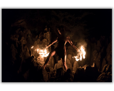 a woman in a black dress is holding a fire