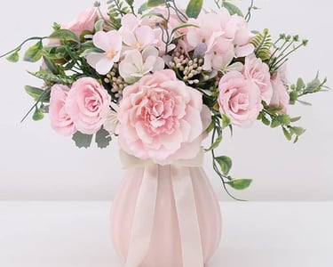 Elegant bouquet of pink silk peonies and roses in a fluted ceramic vase with a ribbon bow.