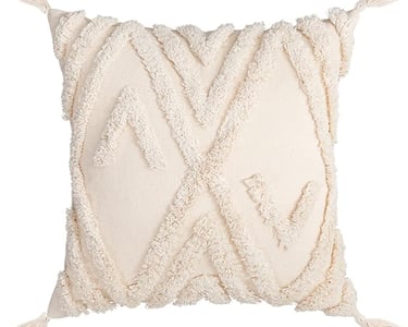 Cream boho decorative throw pillow with tufted geometric patterns and corner tassels.