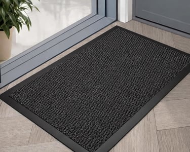 Durable black non-slip indoor outdoor doormat on a herringbone floor by a glass doorway.