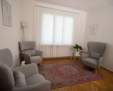 Therapy room of Linda Acikalin with comfortable armchairs, a carpet, and natural light.