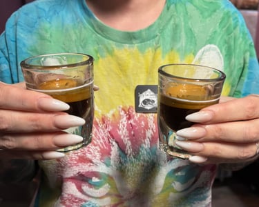 Hands holding two espresso shots