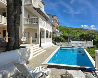 The photo depicts the house and yard with the pool as seen from the western sunny terrace.