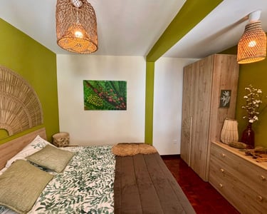 Bohemian bedroom interior with green walls, woven pendant lights, and botanical bedding.