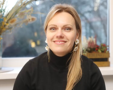 Ievas Sproģes-Grigorjevas portrets. Viņa smaida kamerā, ģērbusies melnā augstapkakles džemperī