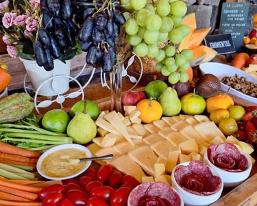 A gourmet charcuterie board featuring artisan cheeses, fresh grapes, berries, and sliced vegetables for a party.